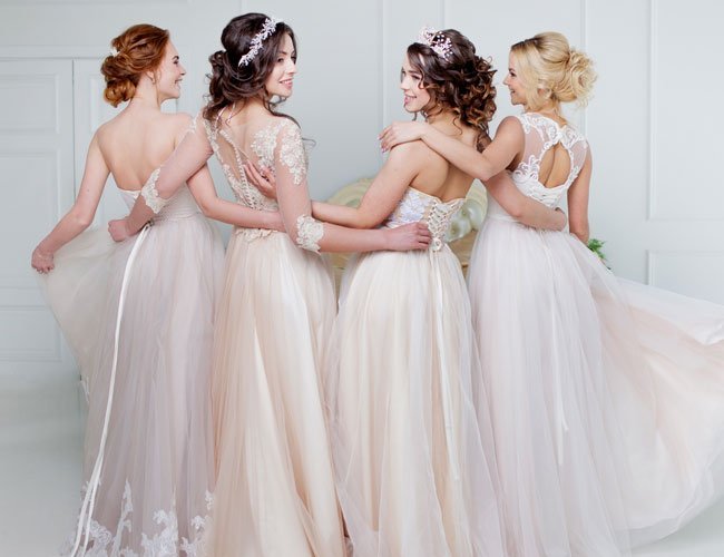Four women in elegant wedding dresses stand together, showcasing their styles and Loxxie Hair hairstyles.