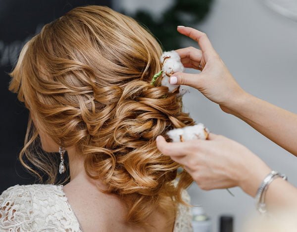 A woman is having her hair styled by a professional at Loxxie Hair, emphasizing the salon's focus on client care.