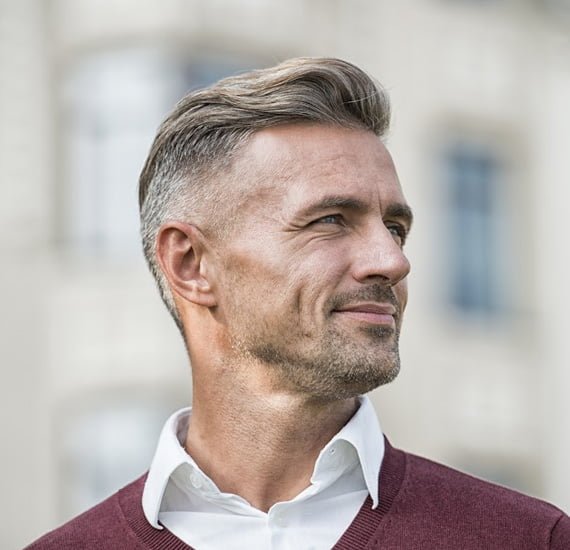 A man in a maroon sweater and white shirt, showcasing Loxxie Hair branding.