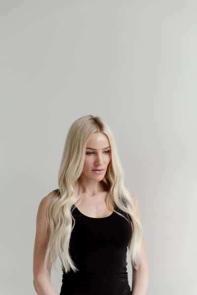 A woman dressed in black leggings and high heels, sporting Loxxie hair, captured in a fashionable stance.