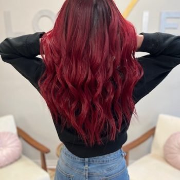 A woman displays her long hair, styled with Loxxie hair, in a bright and cheerful portrait.