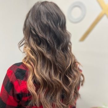 A woman with long wavy hair by Loxxie, dressed in a red plaid shirt, exuding a friendly vibe.