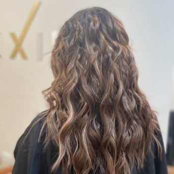 The photo features a woman with flowing long hair styled using Loxxie hair extensions.