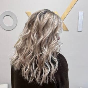 A woman with luxurious long blonde hair, styled using Loxxie hair products, exuding confidence and beauty.