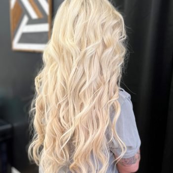 A woman with long blonde hair, enhanced by Loxxie hair products, smiles in a close-up photo.