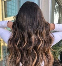 Long wavy hair featuring dark brown highlights, styled with Loxxie hair products for a vibrant look.