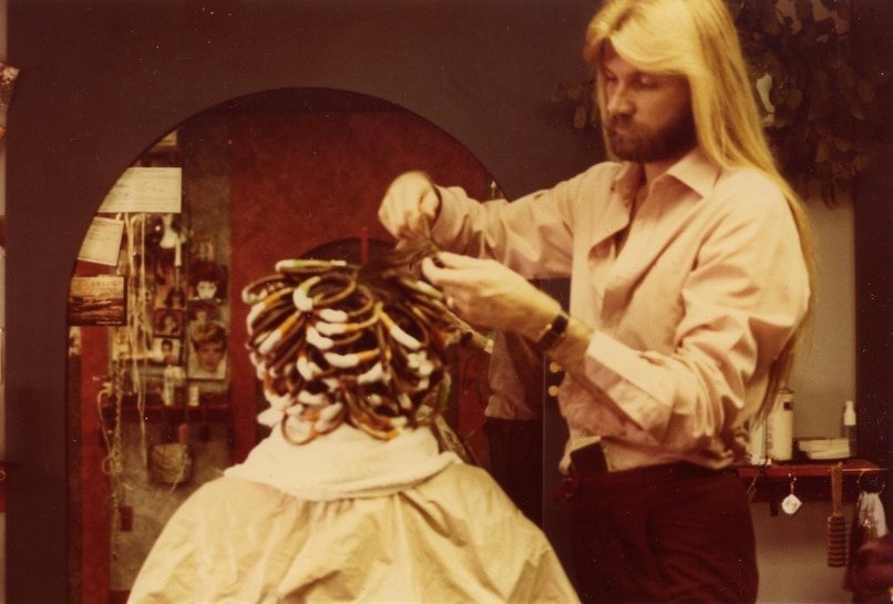 A man with long hair receiving a hairstyle treatment at Loxxie Hair salon.