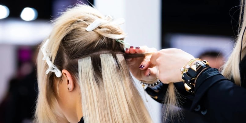 A woman receiving a hair treatment at Loxxie Hair salon, seated in a salon chair with a stylist working on her hair.