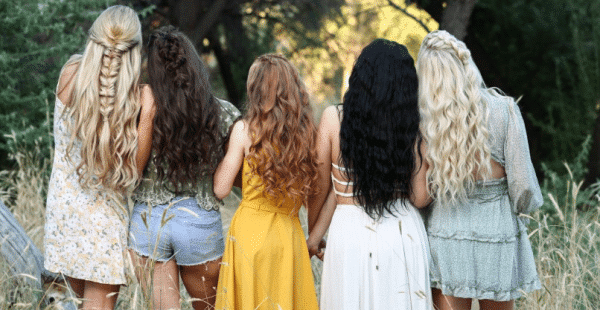 Five women with long hair stand together in a field, showcasing Loxxie Hair products.