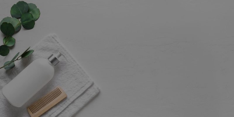 A white towel, Loxxie Hair shampoo bottle, and a brush arranged on a clean white surface.