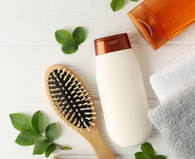 A Loxxie Hair shampoo bottle, a hairbrush, and two towels arranged neatly on a surface.